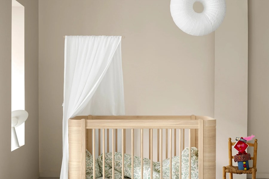 Babybett aus Holz in einem hell eingerichteten Kinderzimmer