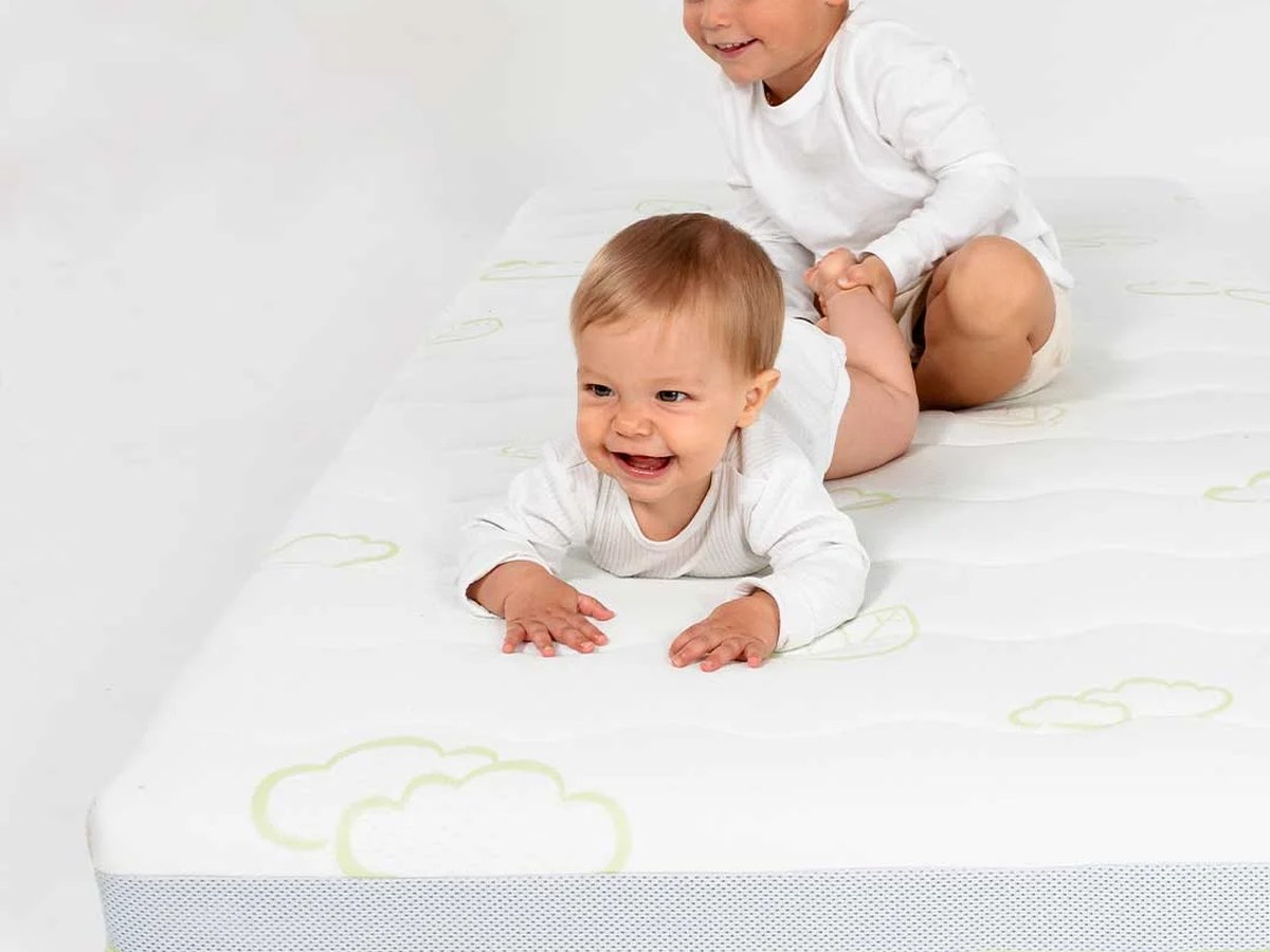 Baby und Kleinkind liegen auf einer Babymatratze