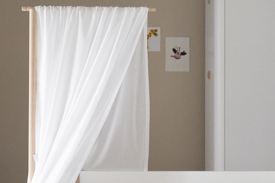 Textilien und Betthimmel im hellen Kinderzimmer